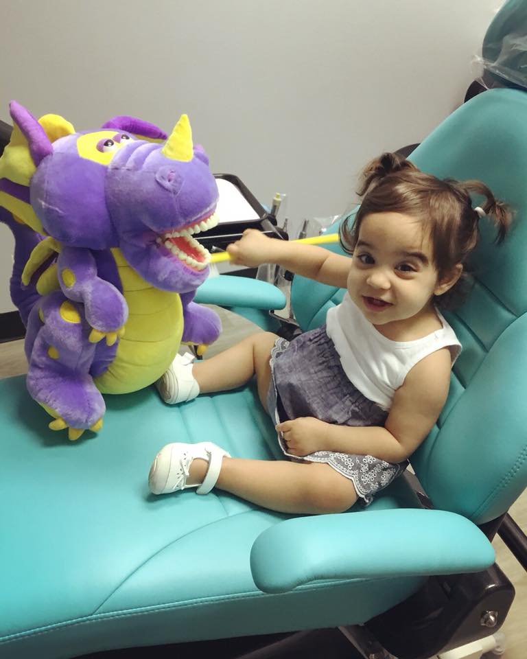 Young patient smiling with a plush dragon at Luv Braces, Austin orthodontist providing friendly care.