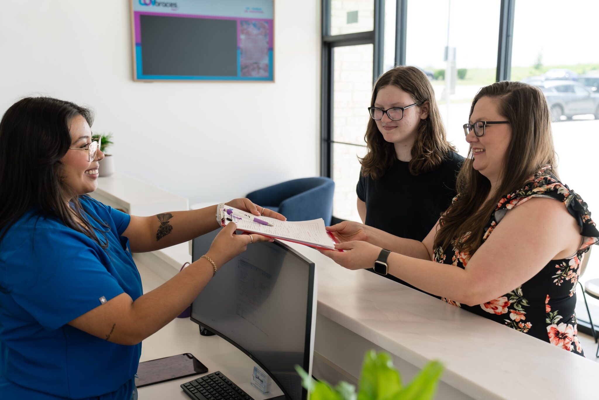 Front desk team member handing forms to a patient at Luv Braces