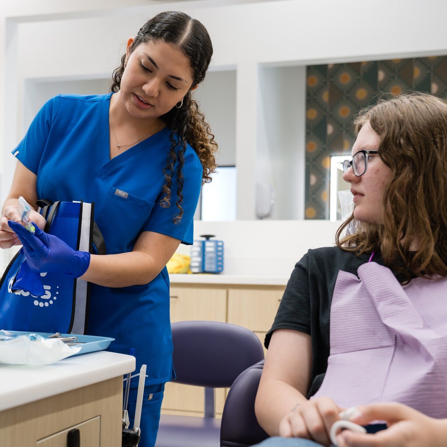 Orthodontic assistant showing braces to a teen patient at Luv Braces